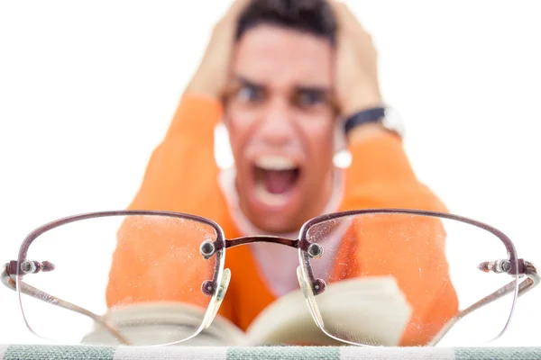 Angry young man with glasses in sweater reading book — Stock Photo, Image