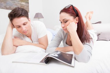 genç bir çift yatakta birlikte dergi okuma
