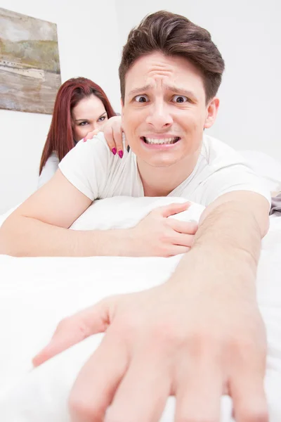 Frightened man trying to escape from the bed because woman — Stock Photo, Image