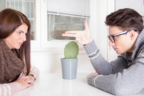 Angry man pointing at woman sitting across the table — Stock Photo, Image