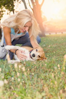 yalan ve köpek çim ile oynarken Jeans gülümseyen sarışın kadın