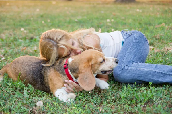 Kvinna ligga och kramas hund på gräset — Stockfoto