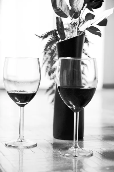 Two glasses of red wine and rose in a vase — Stock Photo, Image