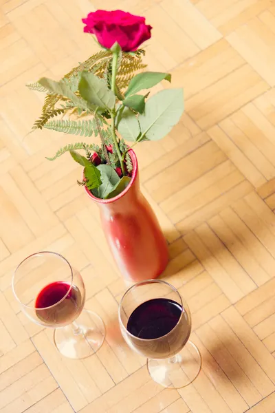 Dwie szklanki czerwonego wina i czerwona róża w wazonie — Zdjęcie stockowe