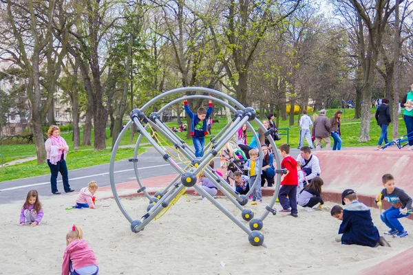 Kinderen klimmen op de jungle gym in zand in het park — Stockfoto