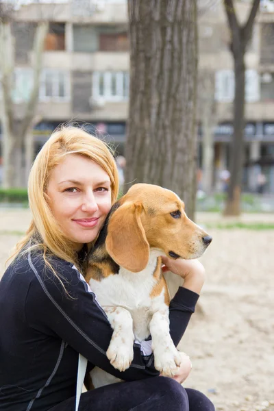 Girl hugging beagle dog in park — Stock Photo, Image