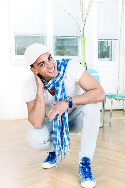 Handsome fashion man with a scarf and white cap posing — Stock Photo, Image