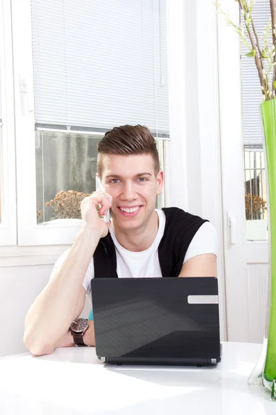 Homem bonito usando laptop e celular — Fotografia de Stock