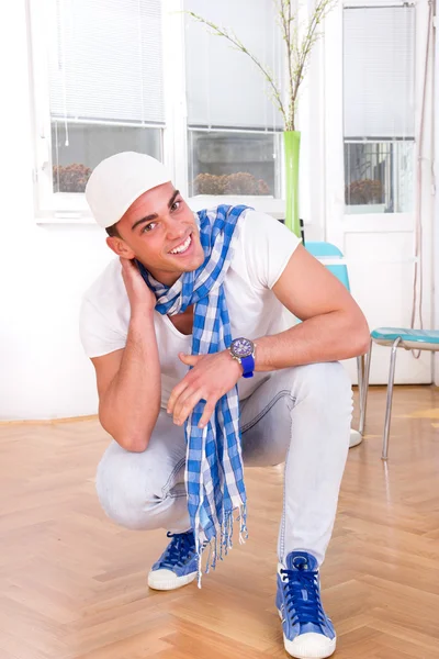 Sorrindo homem de moda bonito com um lenço e boné branco — Fotografia de Stock