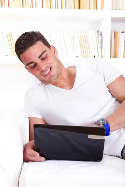Lächelnder junger Mann plaudert zu Hause am Laptop — Stockfoto