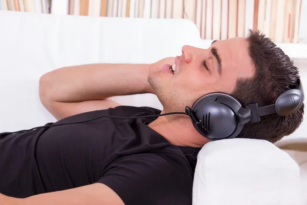 Hombre casual acostado en el sofá escuchando música — Foto de Stock