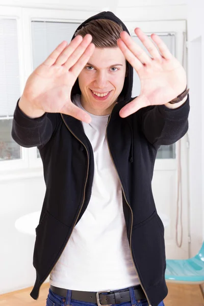 Cool jeune gars en veste à capuchon encadrant son visage avec les mains — Photo