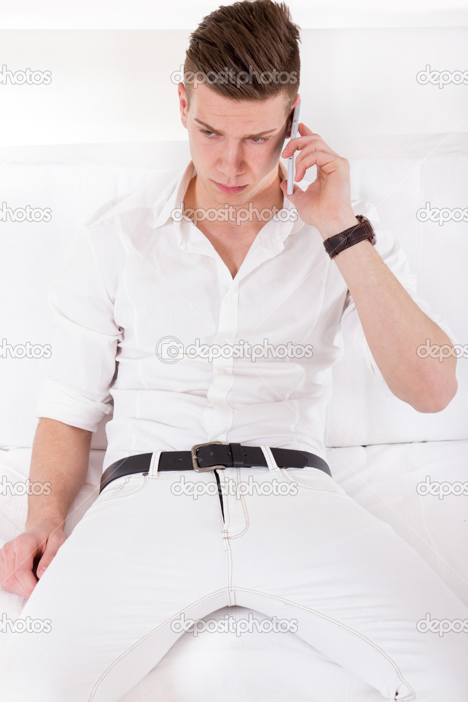 fashionable young handsome man relaxing on couch phoning