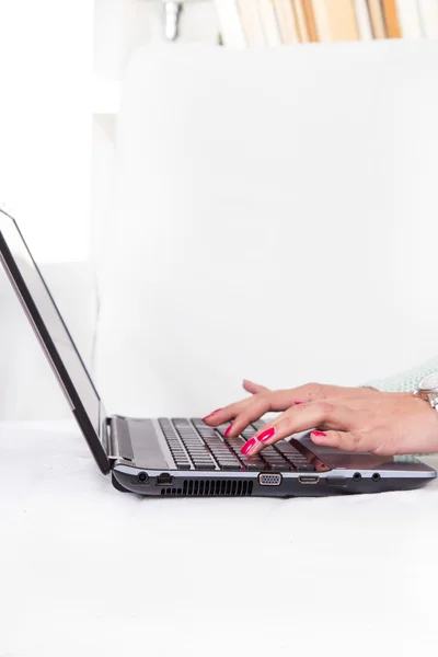 Vrouwelijke handen typen op laptop toetsenbord met rode manicure — Stockfoto