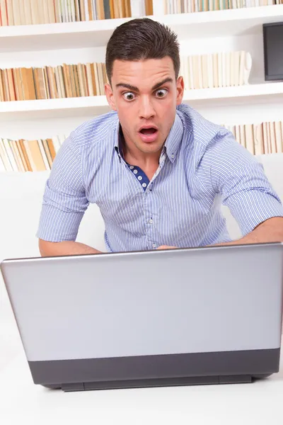 Shocked student sitting in library looking at computer monitor — Stock Photo, Image