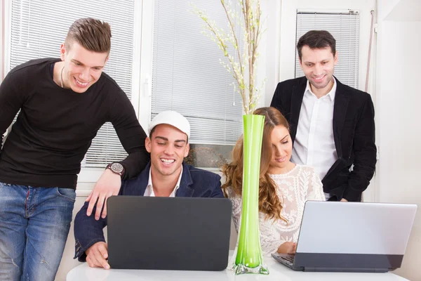 Equipe amigável olhando para o computador portátil sorrindo — Fotografia de Stock