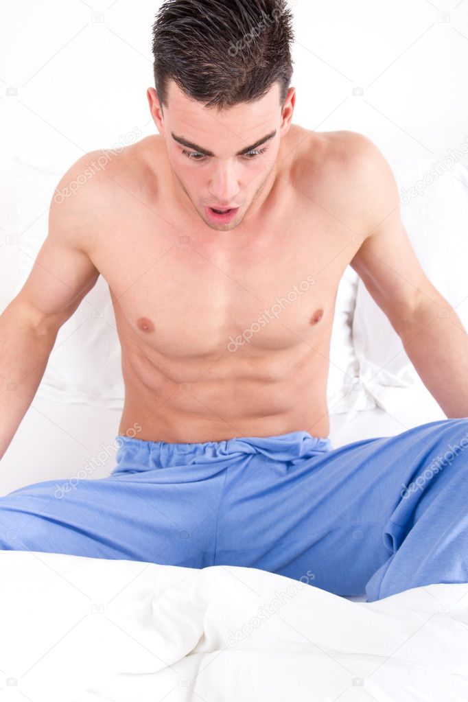 man in bed looking at his genital area having problems
