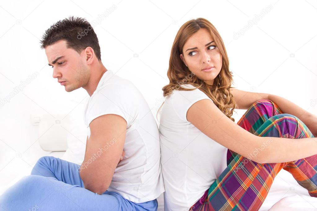 upset couple sitting separate in a bed, having conflict problem