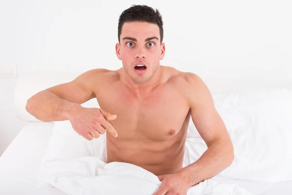 Halv naken ung man i sängen, tittar ner på hans underkläder på Hej Stockbild