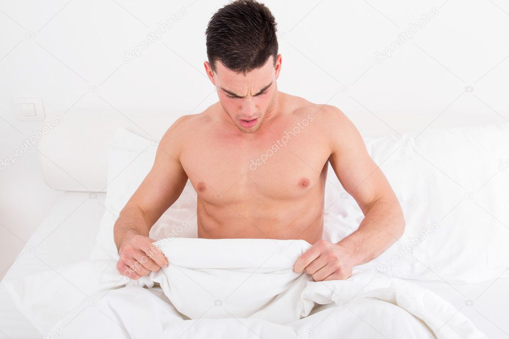  half naked young man in bed  looking down at his underwear