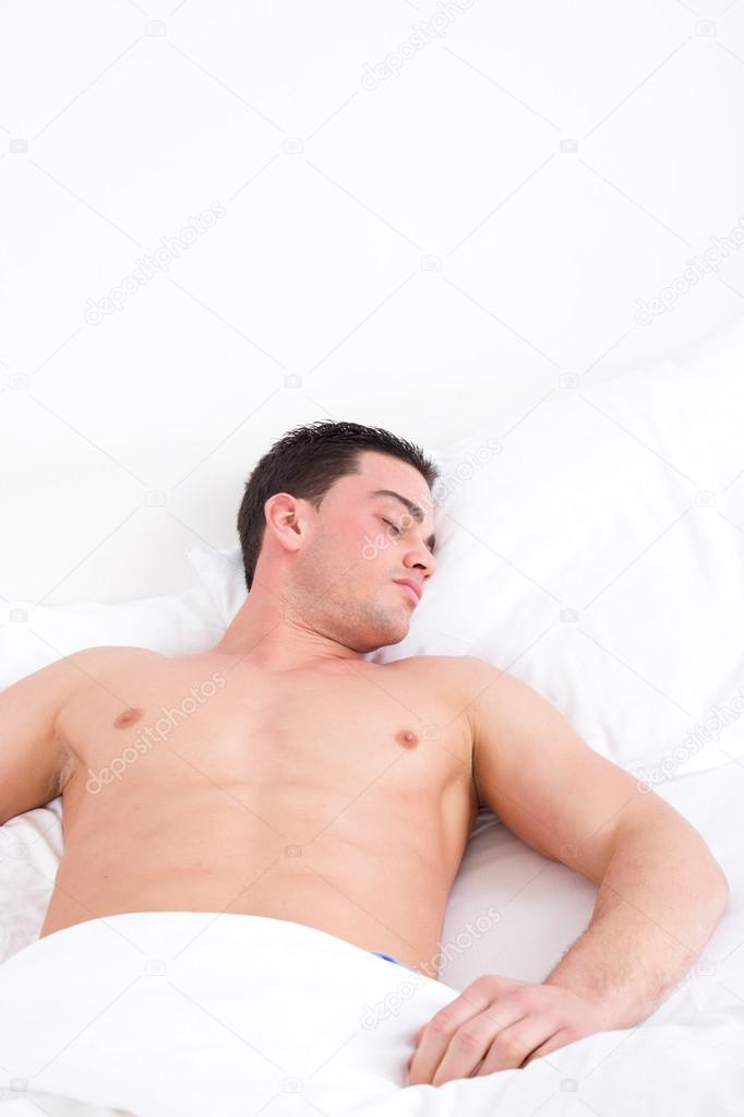 Young caucasian man sleeping in his bed at home