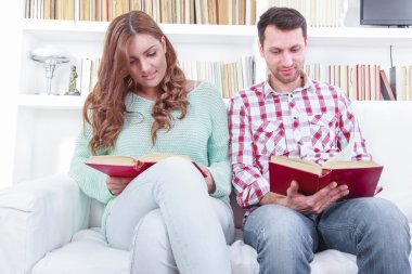 güzel sevgi dolu rahat çift kanepede kitap okuma