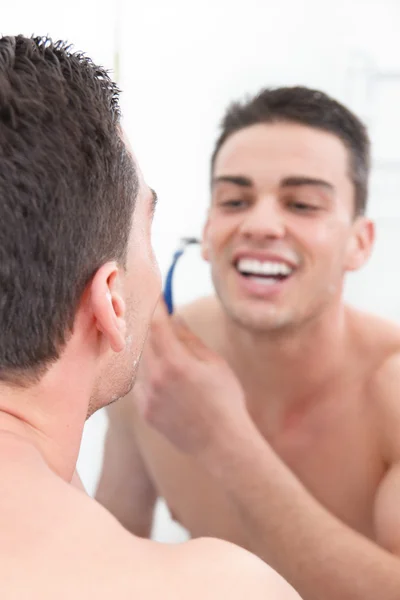 Smiling man shaving in bathroom getting ready for the day — Stock Photo, Image