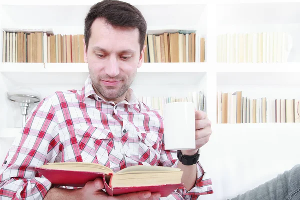 Jonge man op de Bank leesboek ontspannen en genieten van koffie — Stockfoto