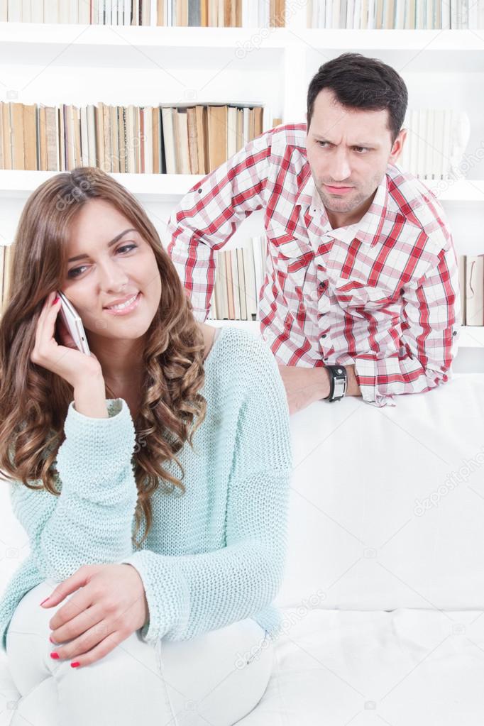 jealous worried man peering over the shoulder of his girlfriend