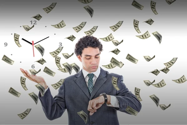 Businessman looking at his watch with money rain around him — Stock Photo, Image