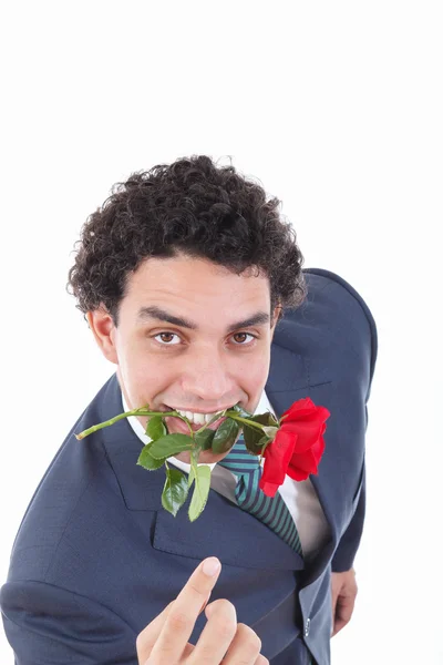 Hombre confiado seductor en un traje con una rosa roja en la boca —  Fotos de Stock