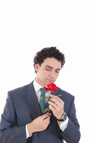 Schöner Mann im Anzug, der eine Rose in der Hand hält und riecht — Stockfoto