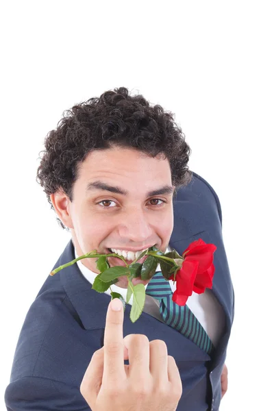 Hombre seductor en un traje sosteniendo una rosa roja en su boca con una sed — Foto de Stock