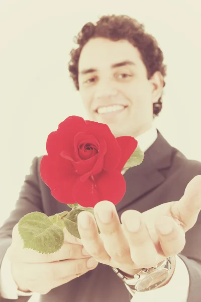 Uomo sorridente in un vestito che tiene una rosa rossa e la offre al ca — Foto Stock