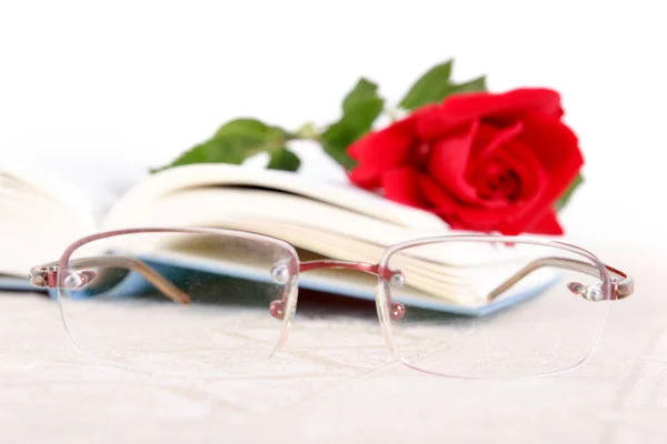 Book and red rose on pages of book on white background with glas — Stock Photo, Image