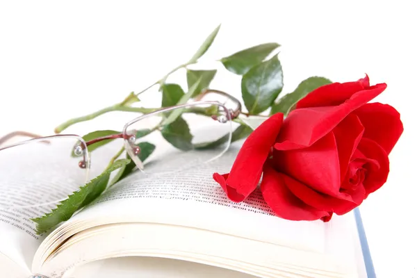 书和戴着眼镜在白色背景上的书页上的红玫瑰 — 图库照片
