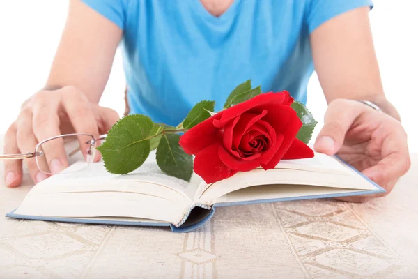 Homme avec ses mains tenant livre ouvert tandis que rose et lunettes sont — Photo