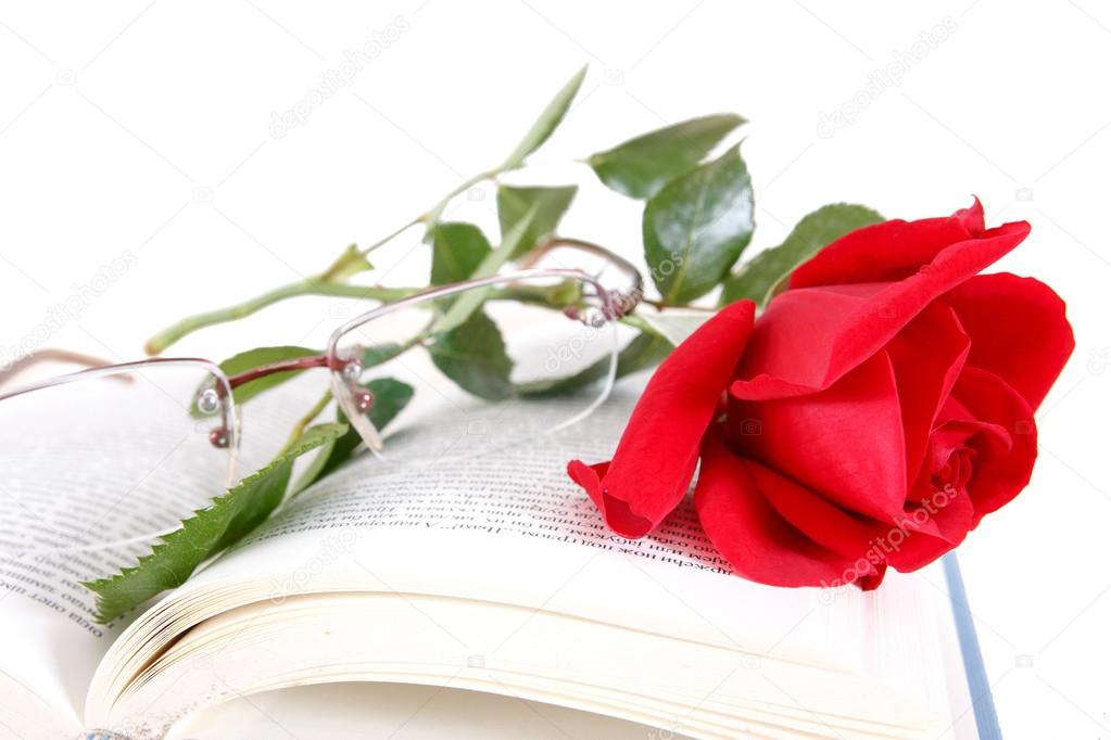 book and red rose with glasses on pages of book on white backgro