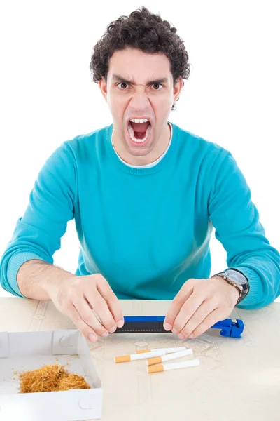 Angry man in blue sweater making cigarettes with device for ciga — Stock Photo, Image