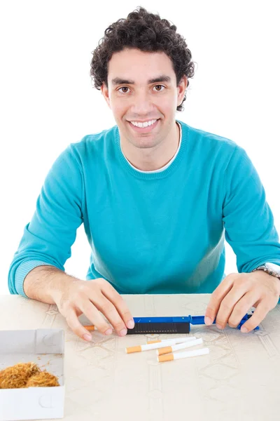 Man in blue sweater making cigarettes with device for cigar and — Stock Photo, Image