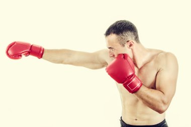 Muscular man wearing red boxing gloves and punching  clipart