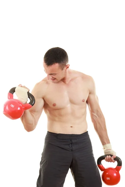 Athletic man holding and lifting up red kettlebells weights one — Stock Photo, Image