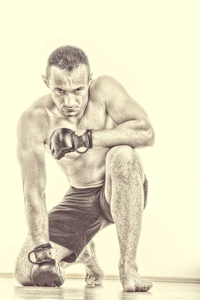 MMA fighter med kampen handskar be för segern medan kneelin — Stockfoto