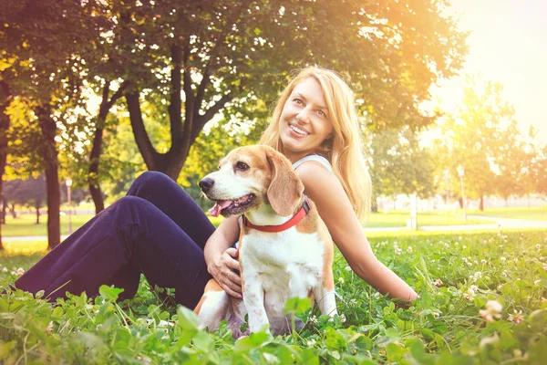 Young woman embracing her beagle puppy dog in the park — Stock Photo, Image