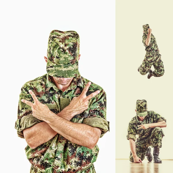 Soldado con cara oculta en uniforme de camuflaje verde saltando y — Foto de Stock