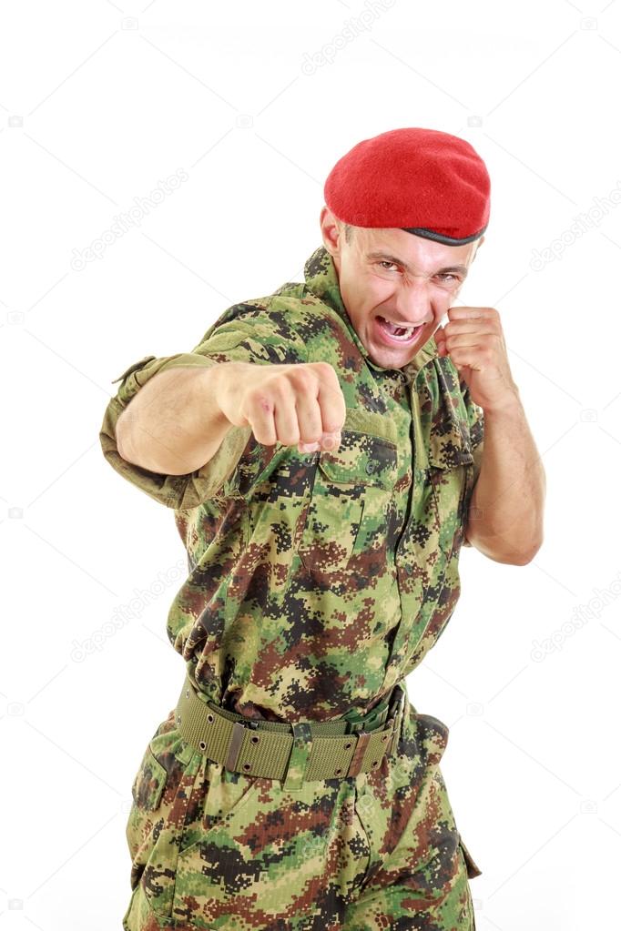 Angry military soldier in uniform and cap hitting with fist