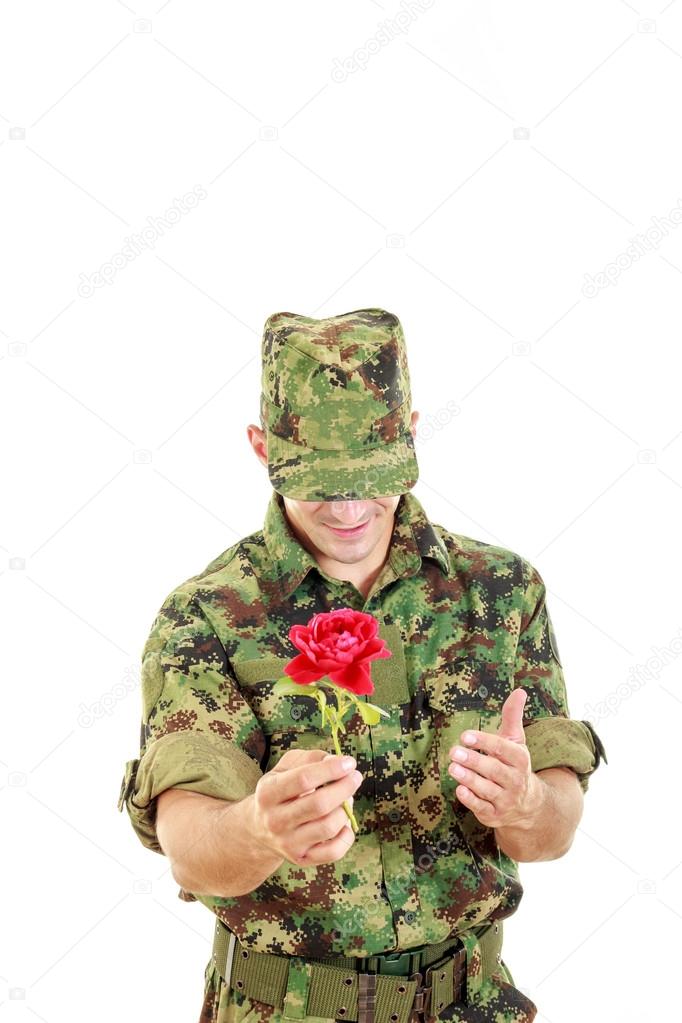 Military officer holding flower smiling shy with head bowed