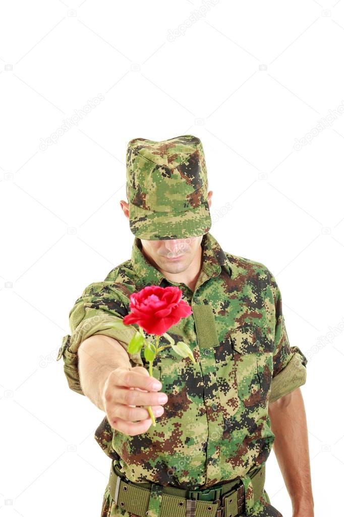 Romantic soldier in military uniform offering red rose