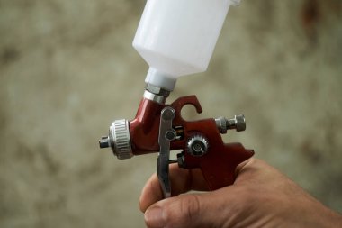 Bir insan elinde bir sprey tabanca tutuyor.