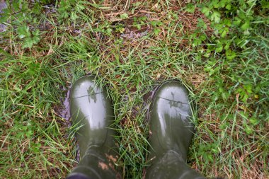 Nisan 'da çayırdaki yağmurda lastik botların içinde ayaklar